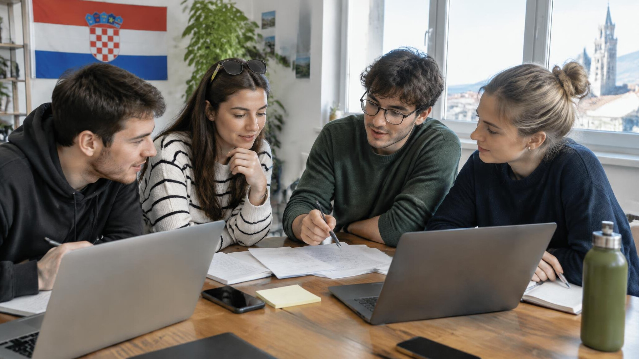 Group of people collaborating around a table with laptops and notes